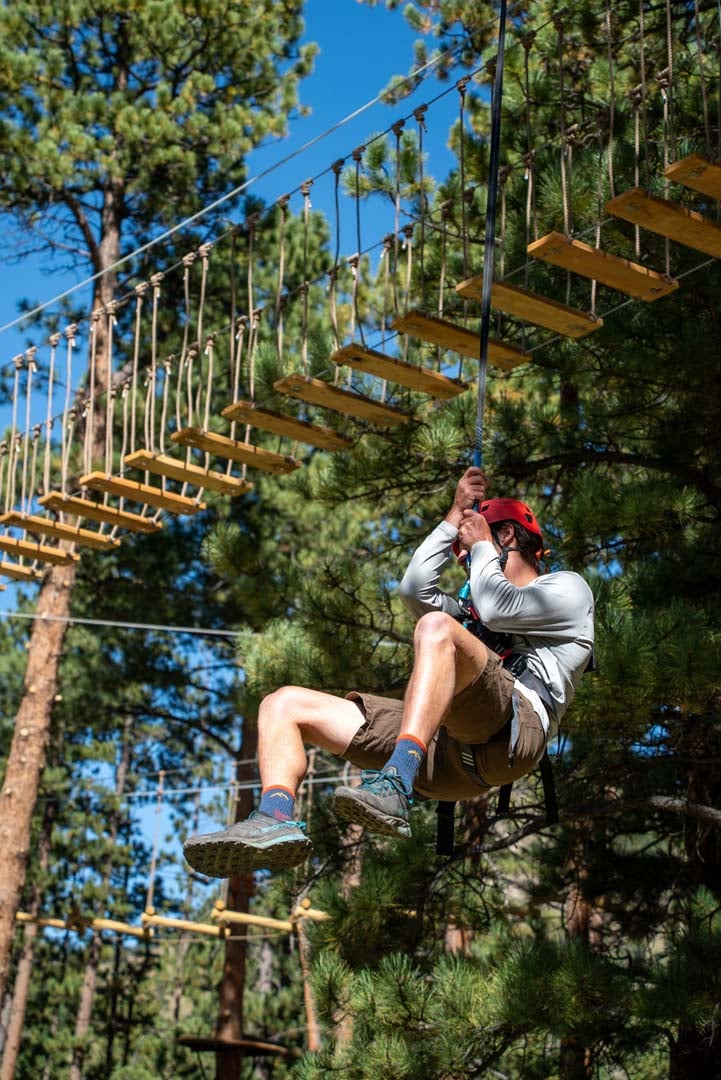 Man hanging from a tree in an outdoor climbing course