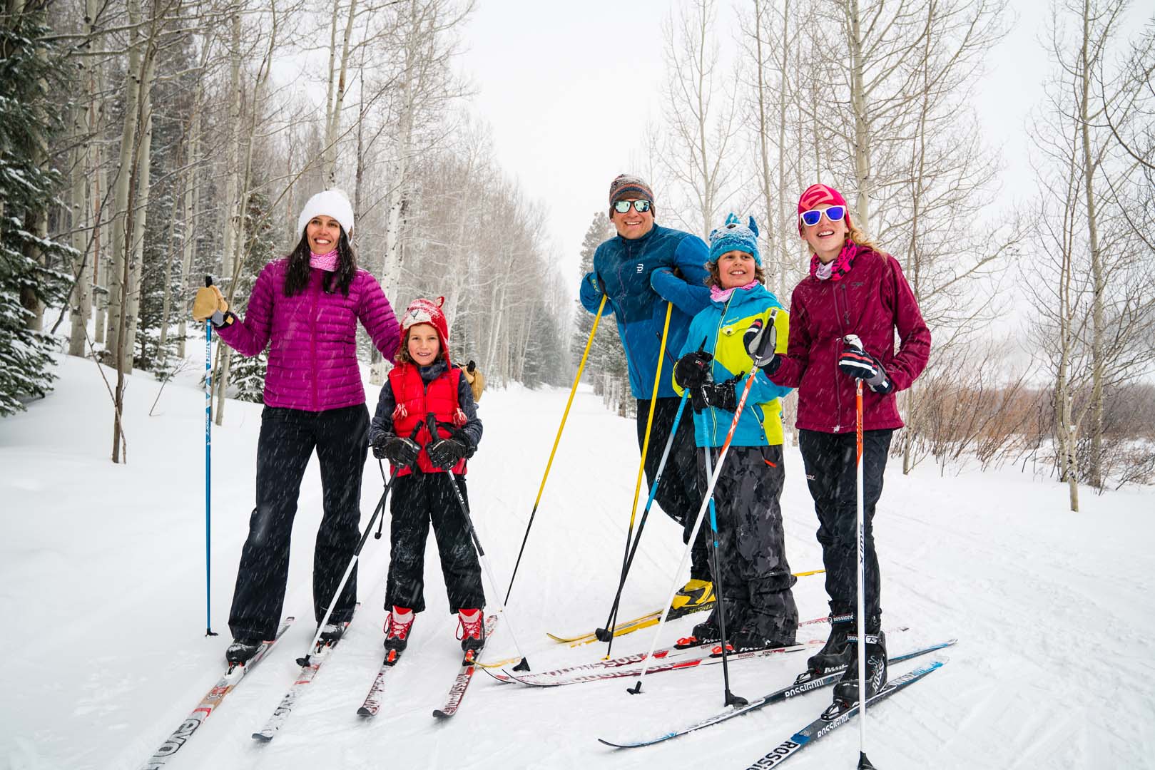 Four people cross country skiing with trees surrounding