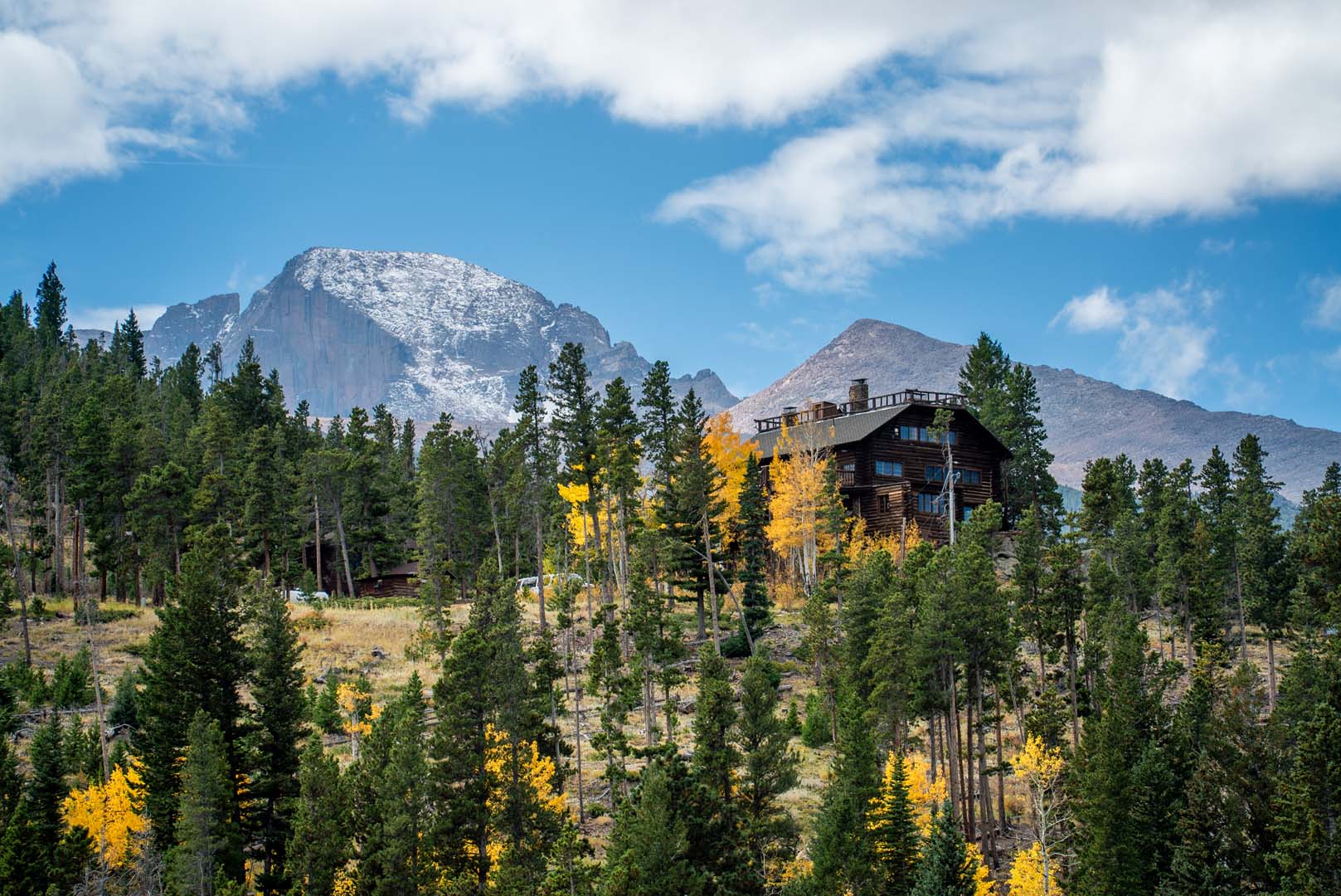 Landscape photo of mountains, trees and cabin