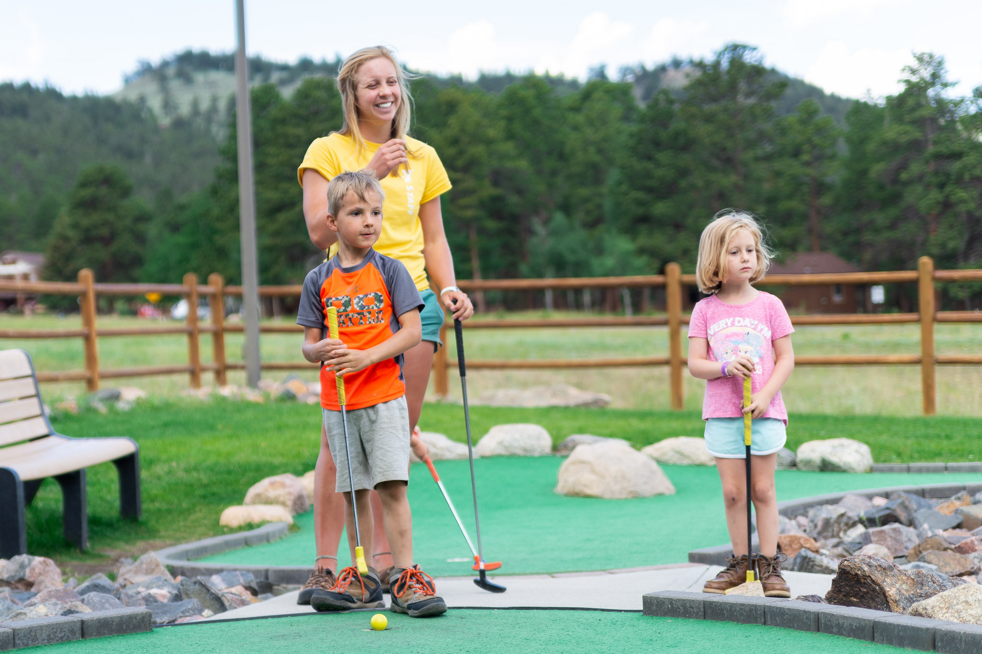 Adulto y dos niños jugando al minigolf.