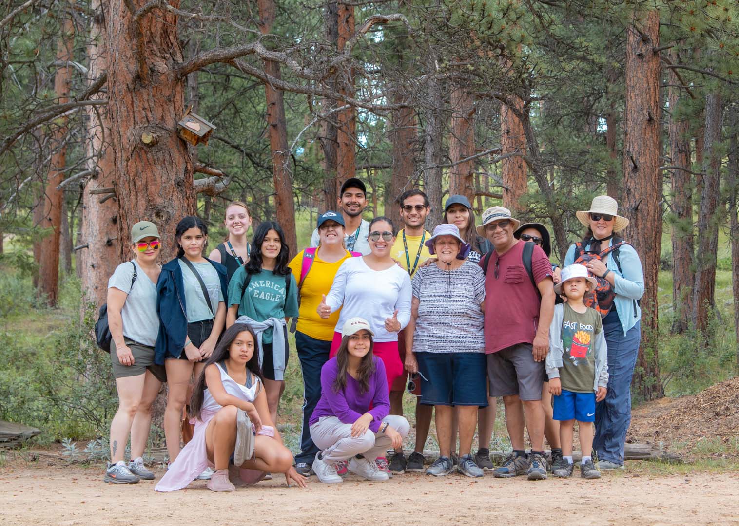 Group of people posing for a photo outside in front of woods