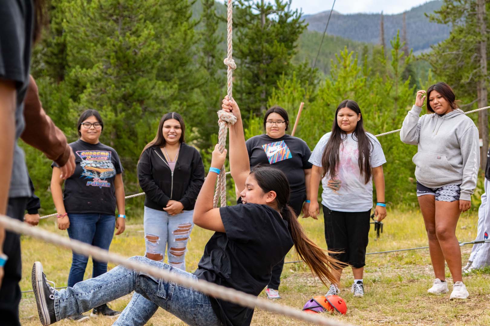 Children playing outside, one girl on a rope swing while everyone else watches