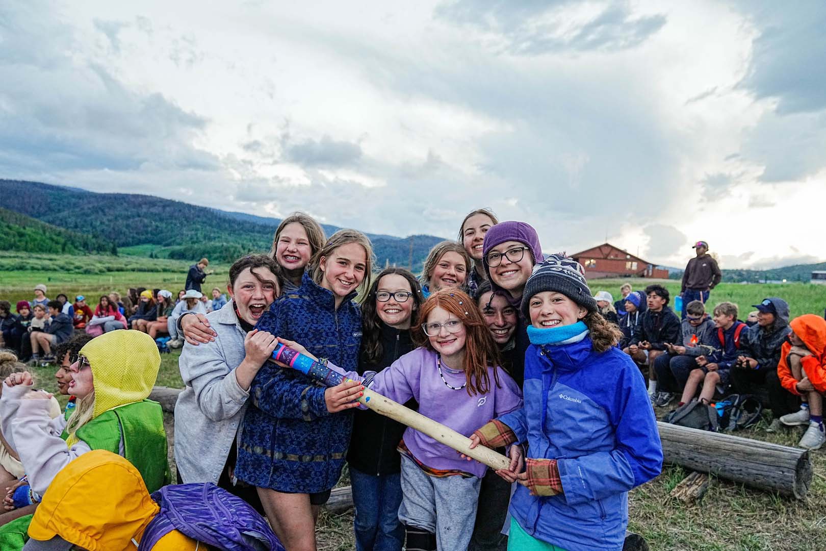 Group of children outside playing during camp holding a wooden stick