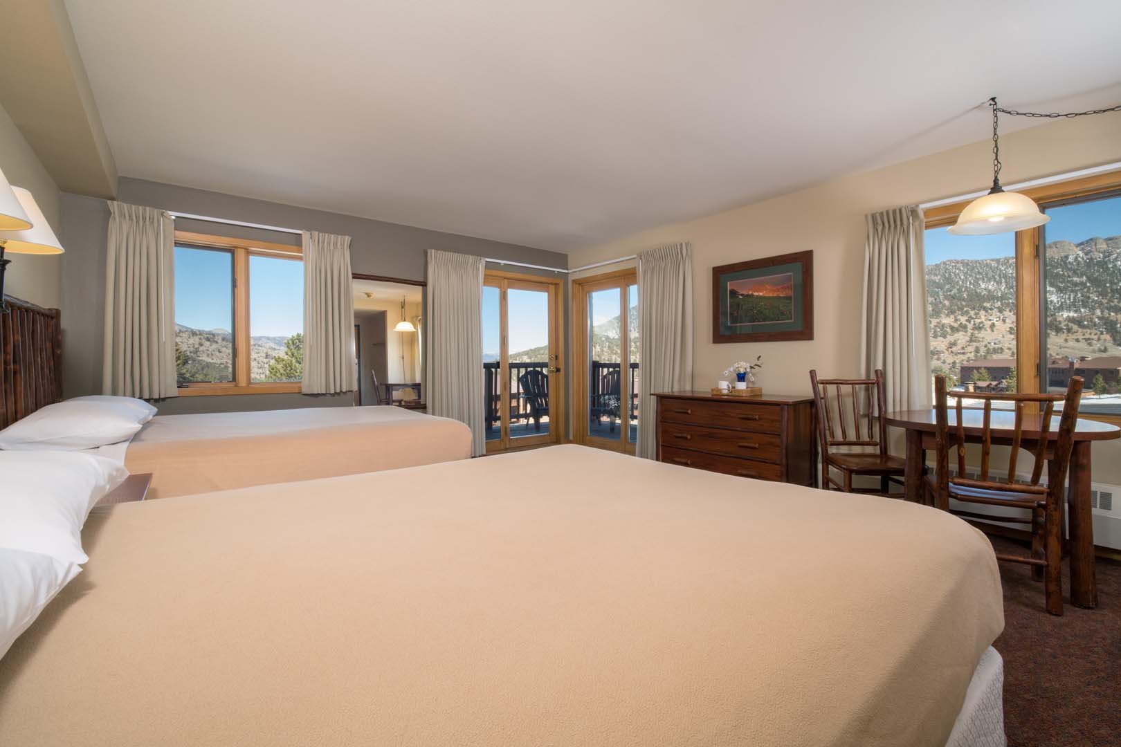 Two beds in lodge room with view of mountains and table with chairs