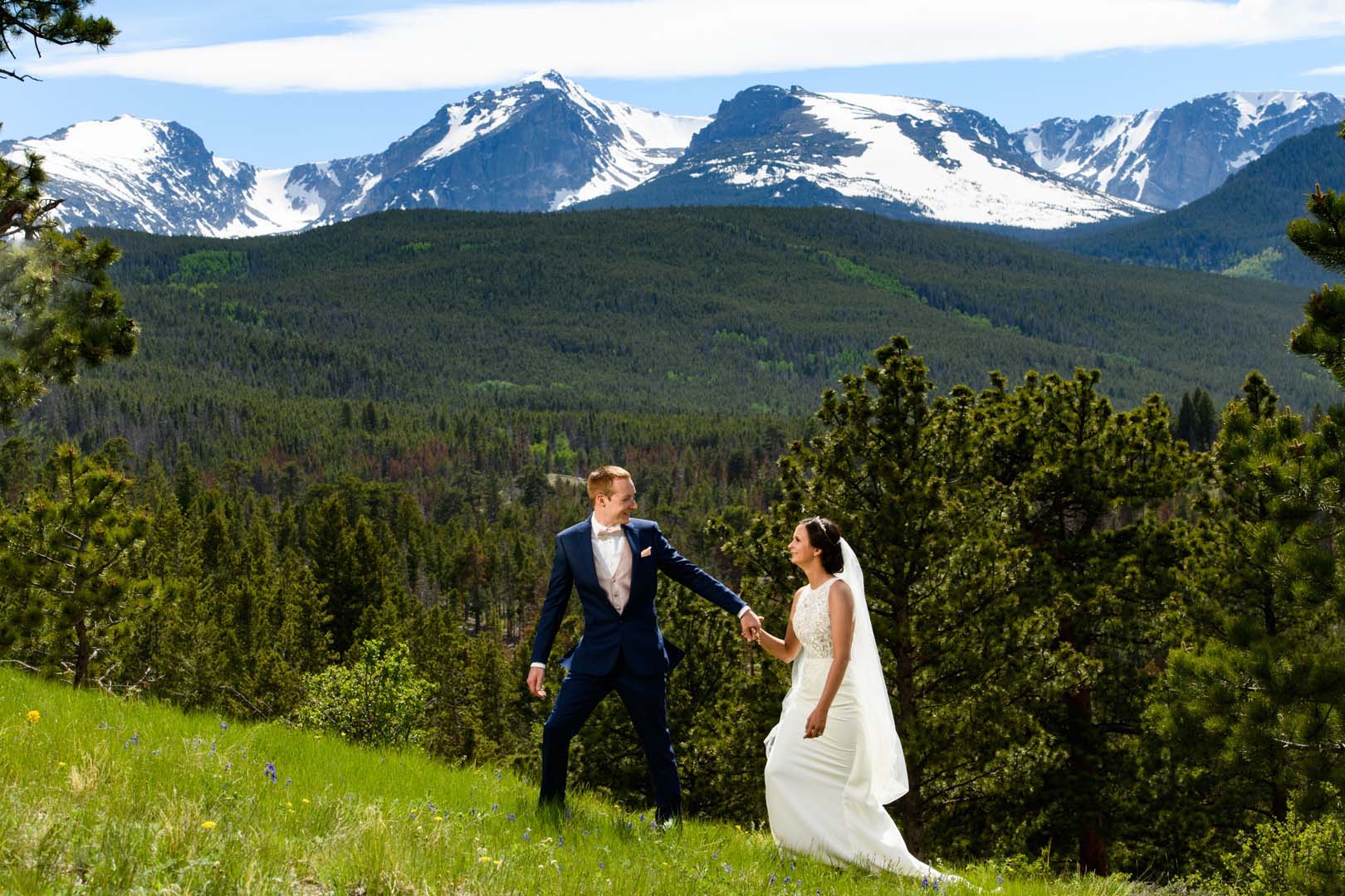 Couple walking in the grass with beautiful snow capped mountains in the background