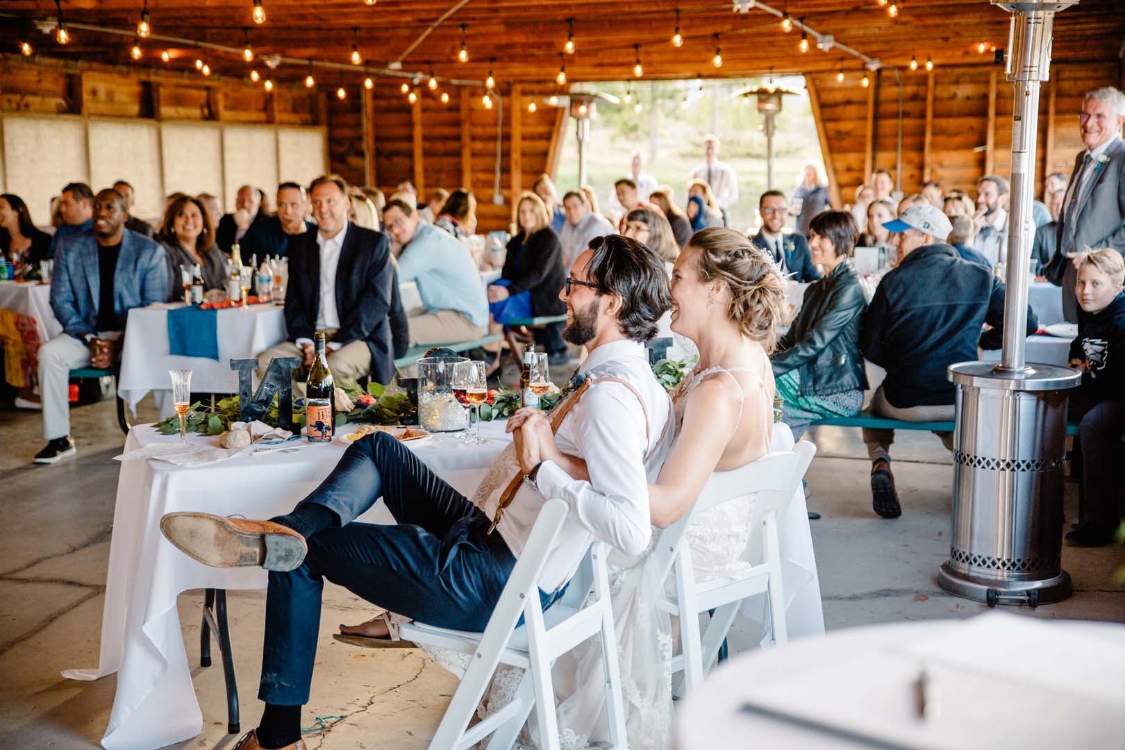 Group of people inside at a wedding, the married couple is sitting and smiling.