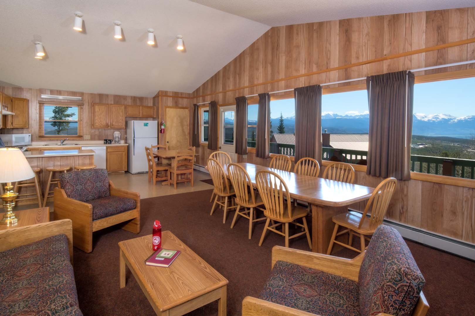 living room area with kitchen, dining table and sofas with view of mountains