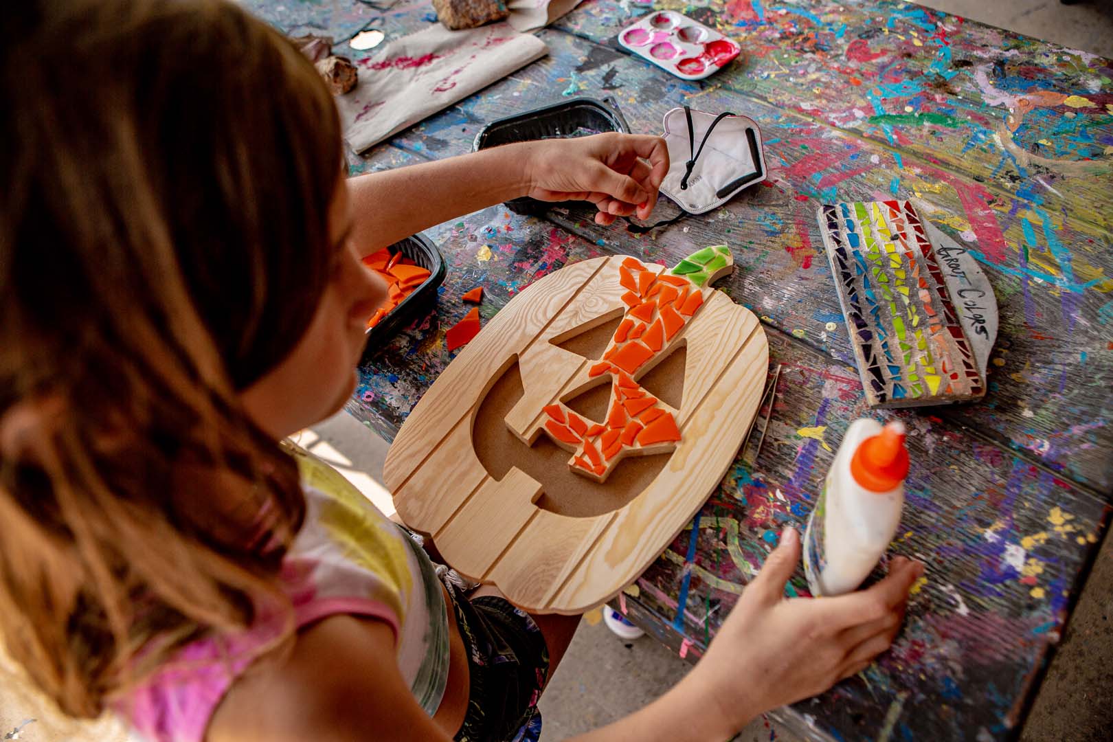 niña decorando una calabaza en la mesa de artes y manualidades