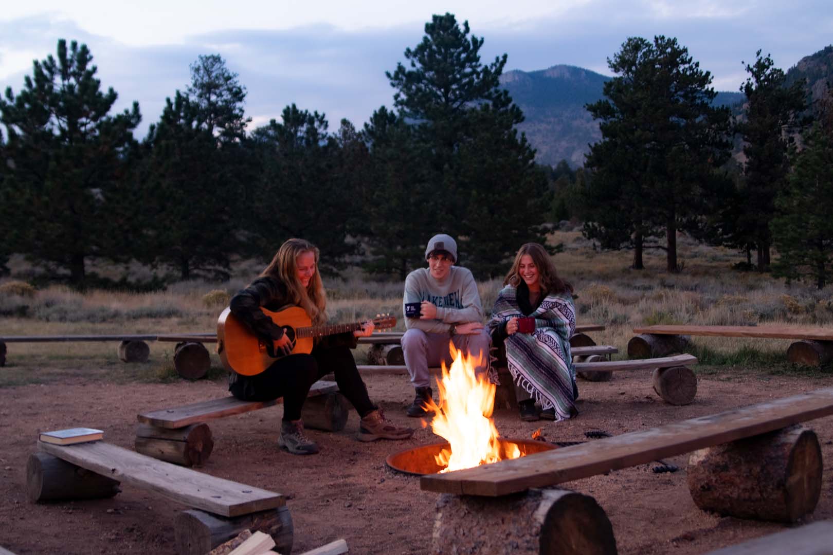 people at camp fire with guitar
