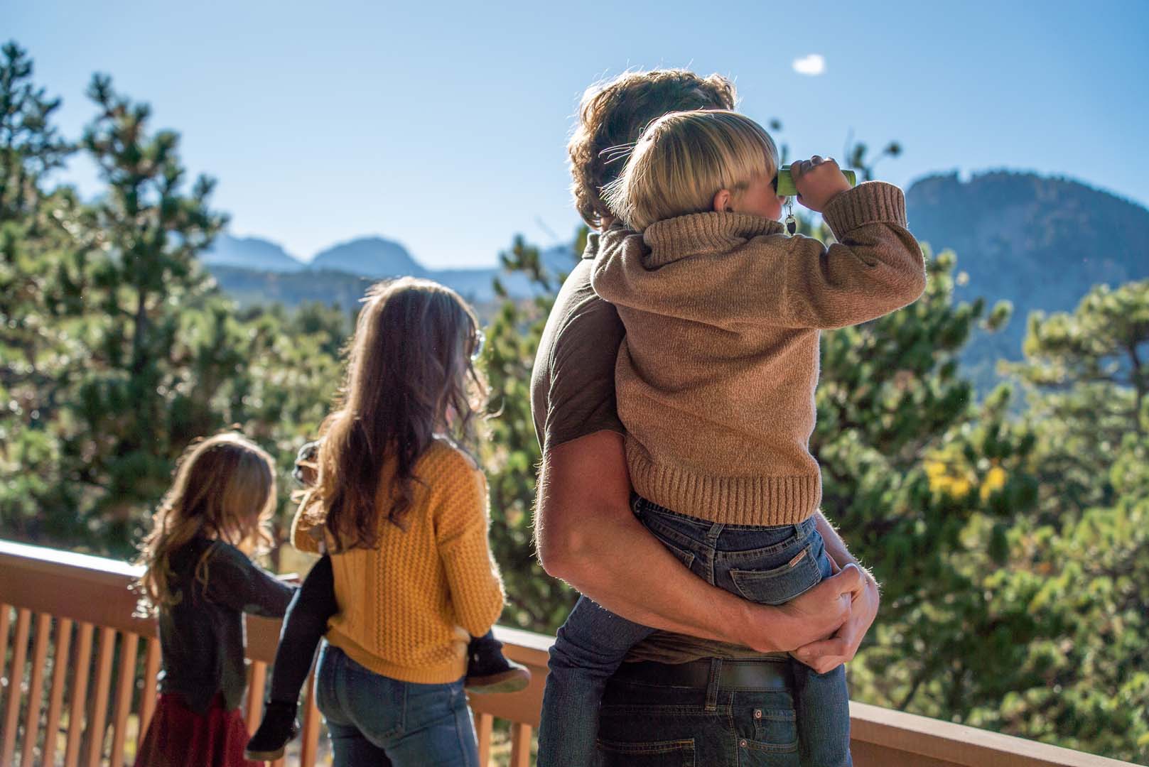 Kids looking out at the trees and mountains with binoculars