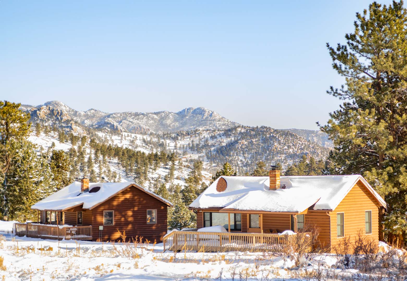 cabañas con nieve encima con la montaña al fondo