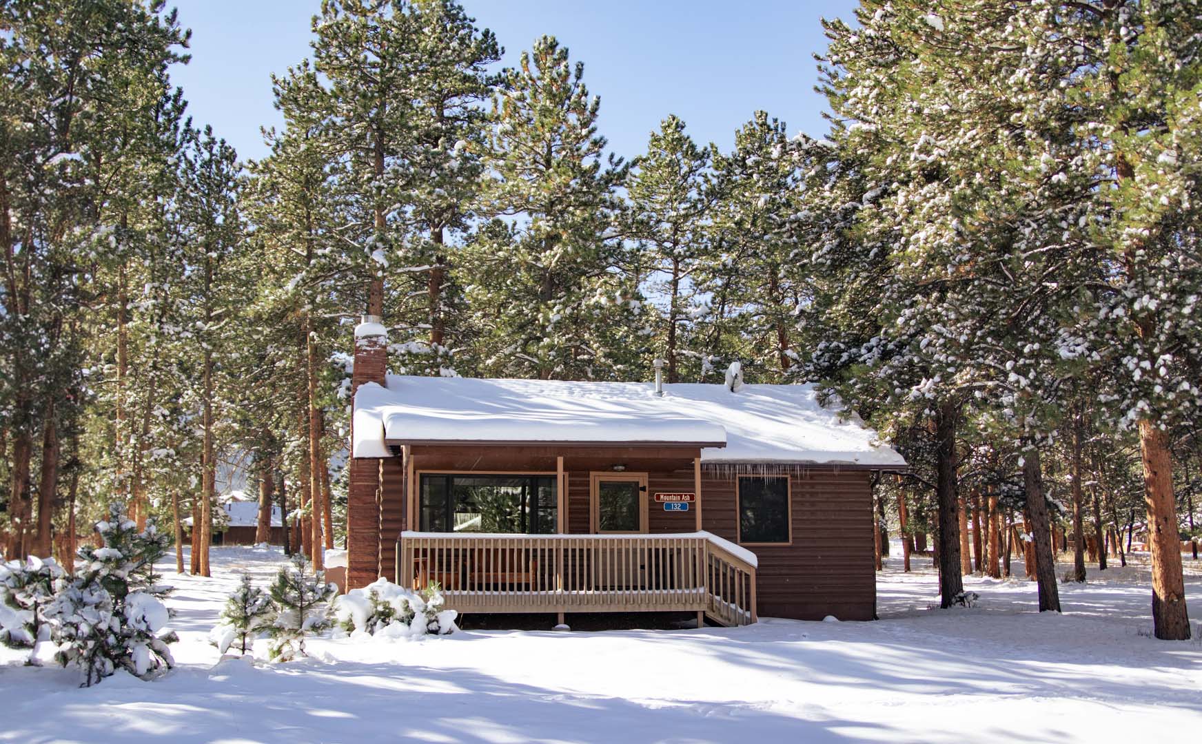 cabin with snow on top of it with trees in the background