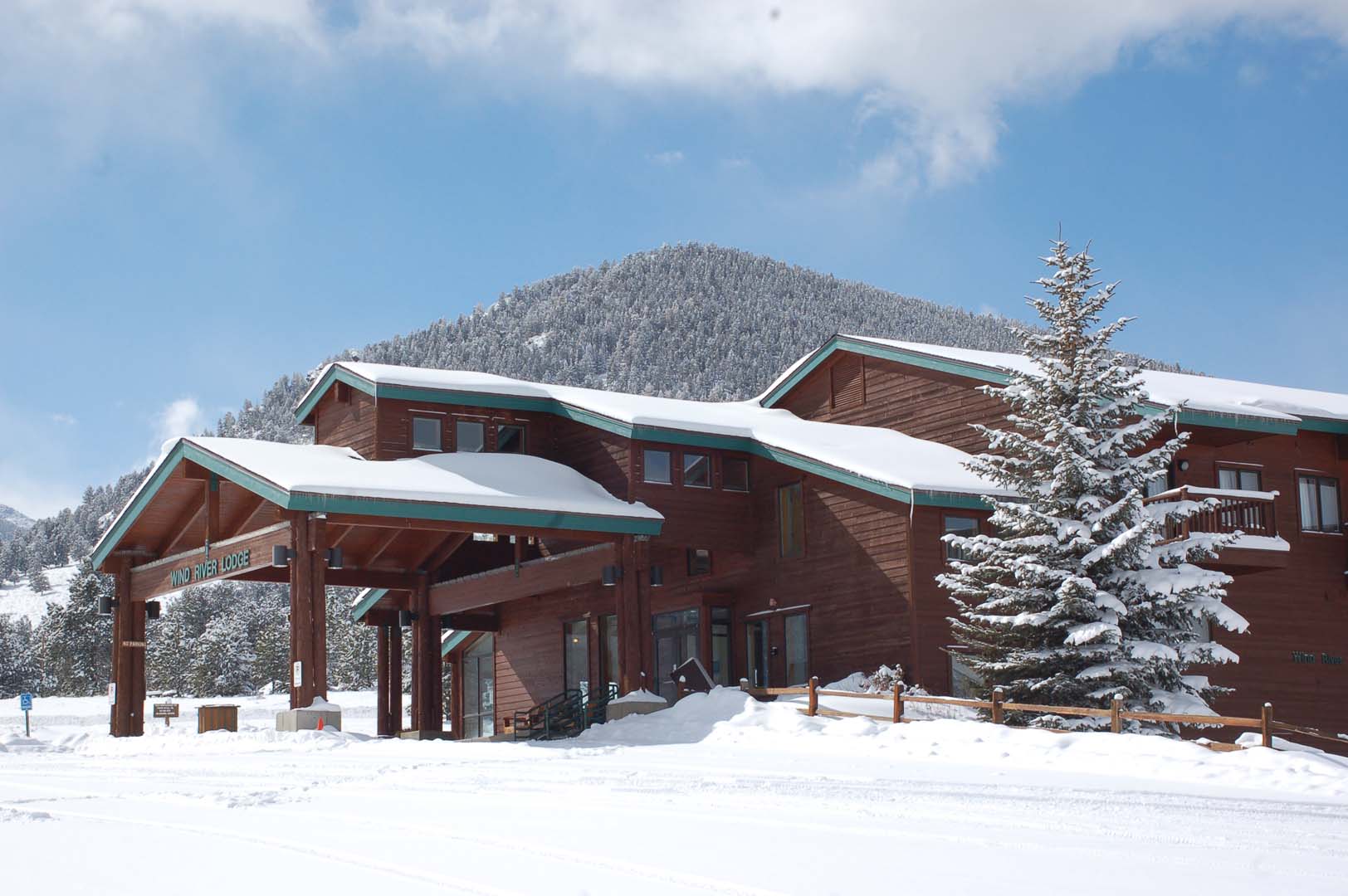 cabin with snow on top of it with mountain in the background