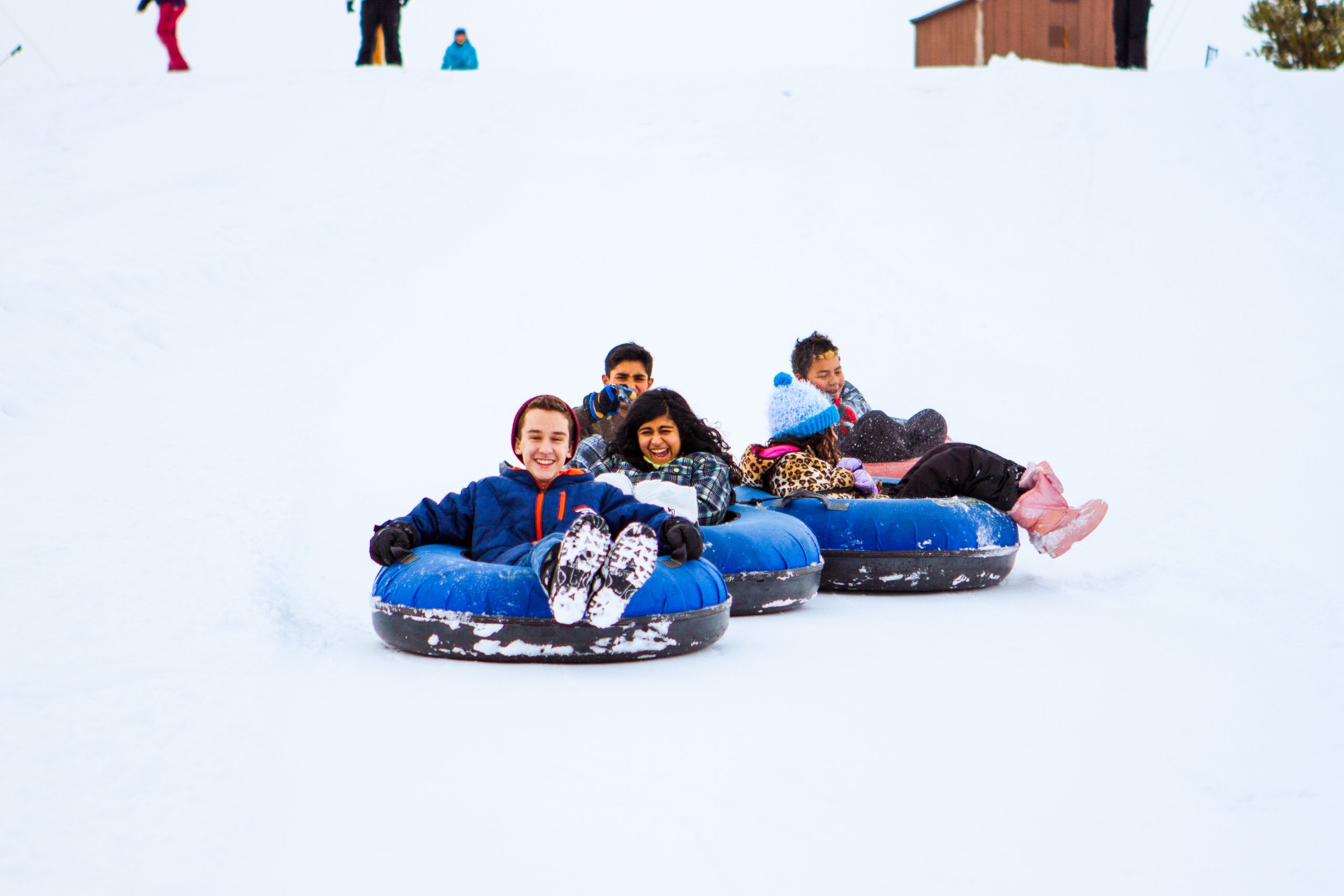 Niños haciendo tubing en invierno bajando una colina nevada