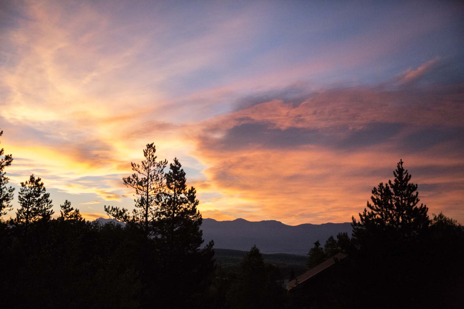 cielo del atardecer con árboles y montañas