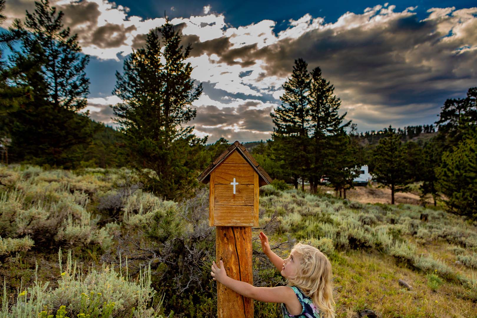 Chica en el bosque junto a una caja de madera religiosa.