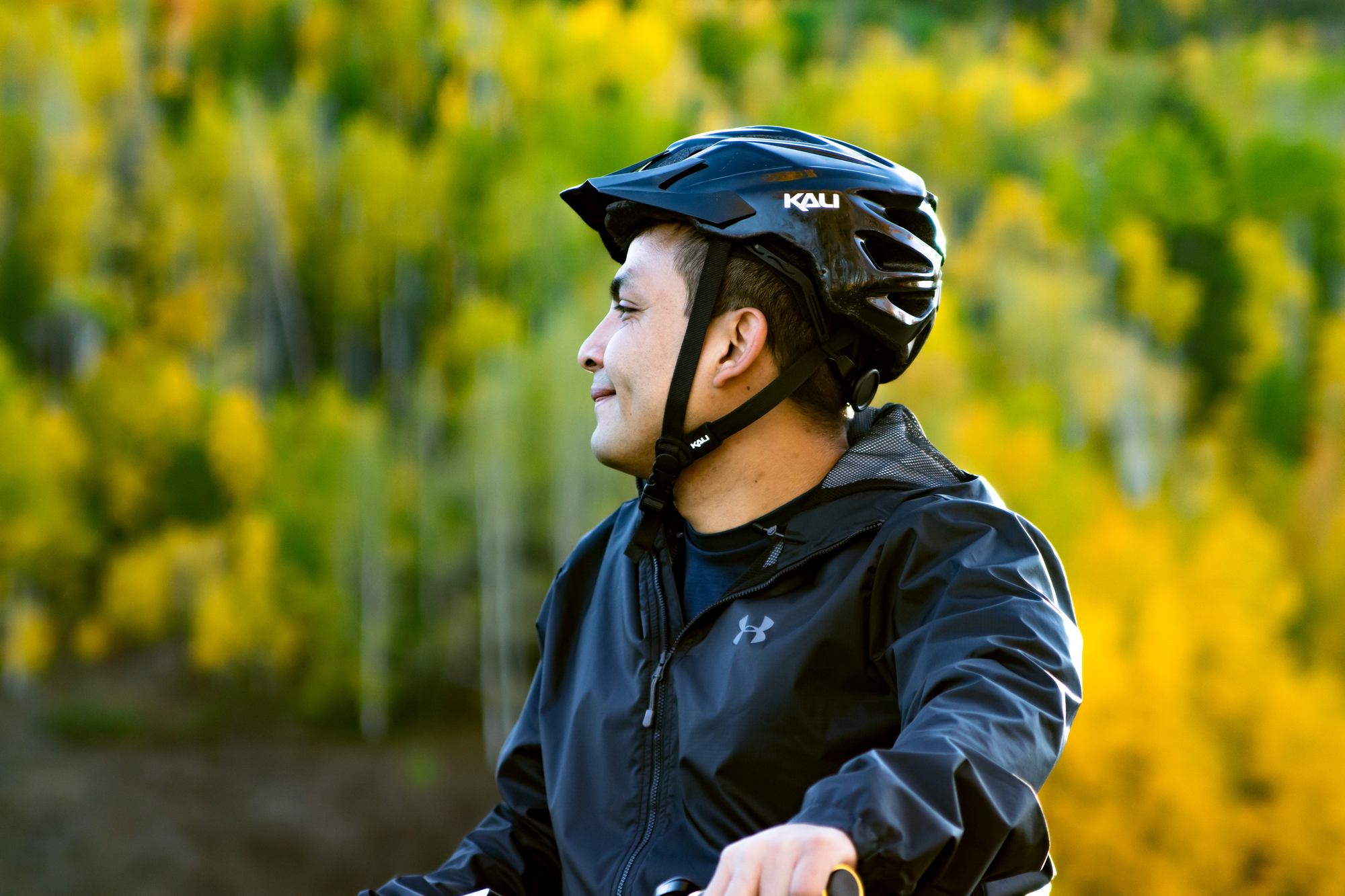 cabeza de hombre con casco de bicicleta con árboles en el fondo