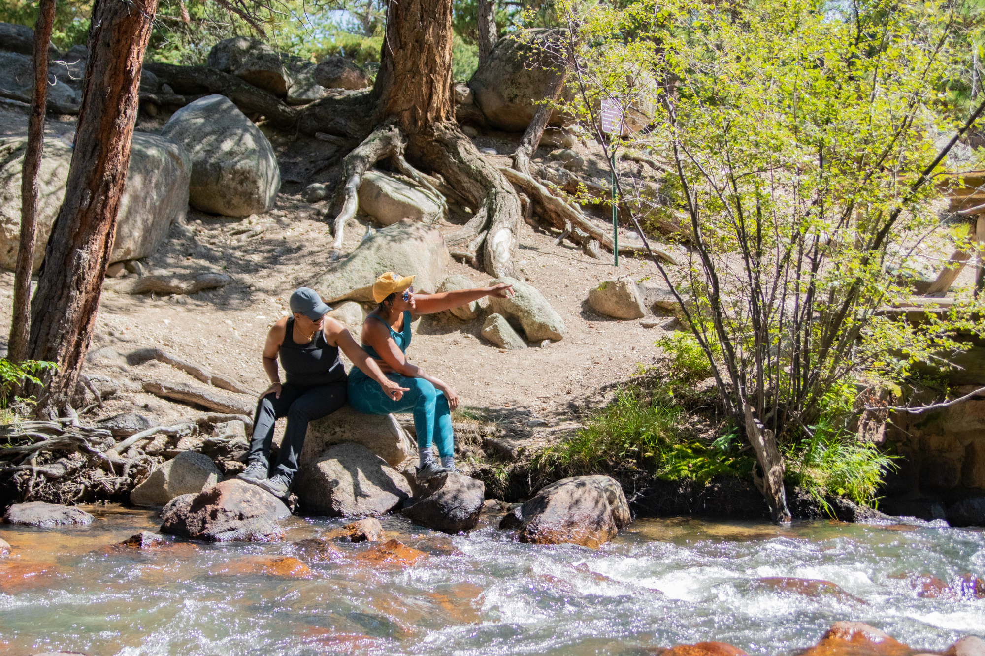 two women sitting by a river