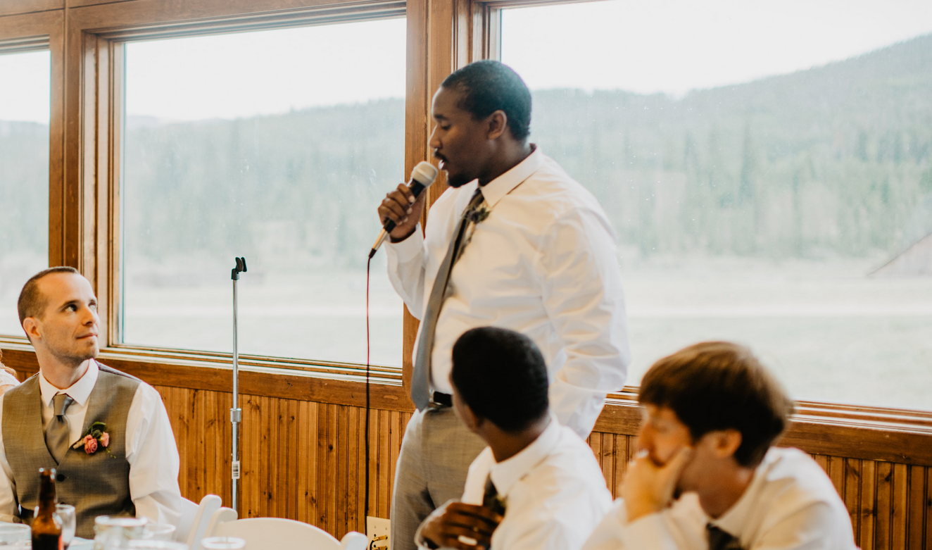 man speaking at wedding reception table