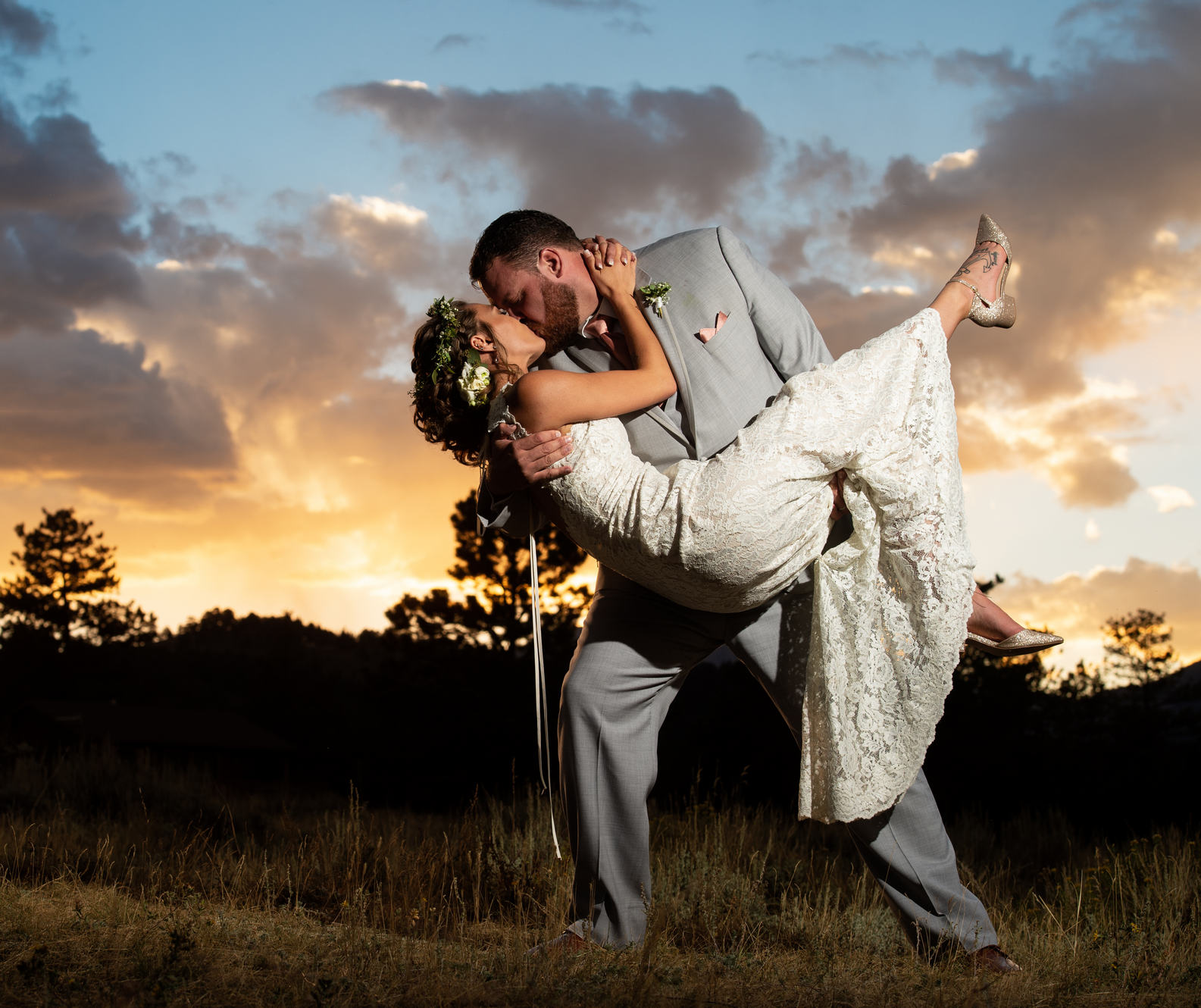 bride and groom kissing with sunset and mountains in the background